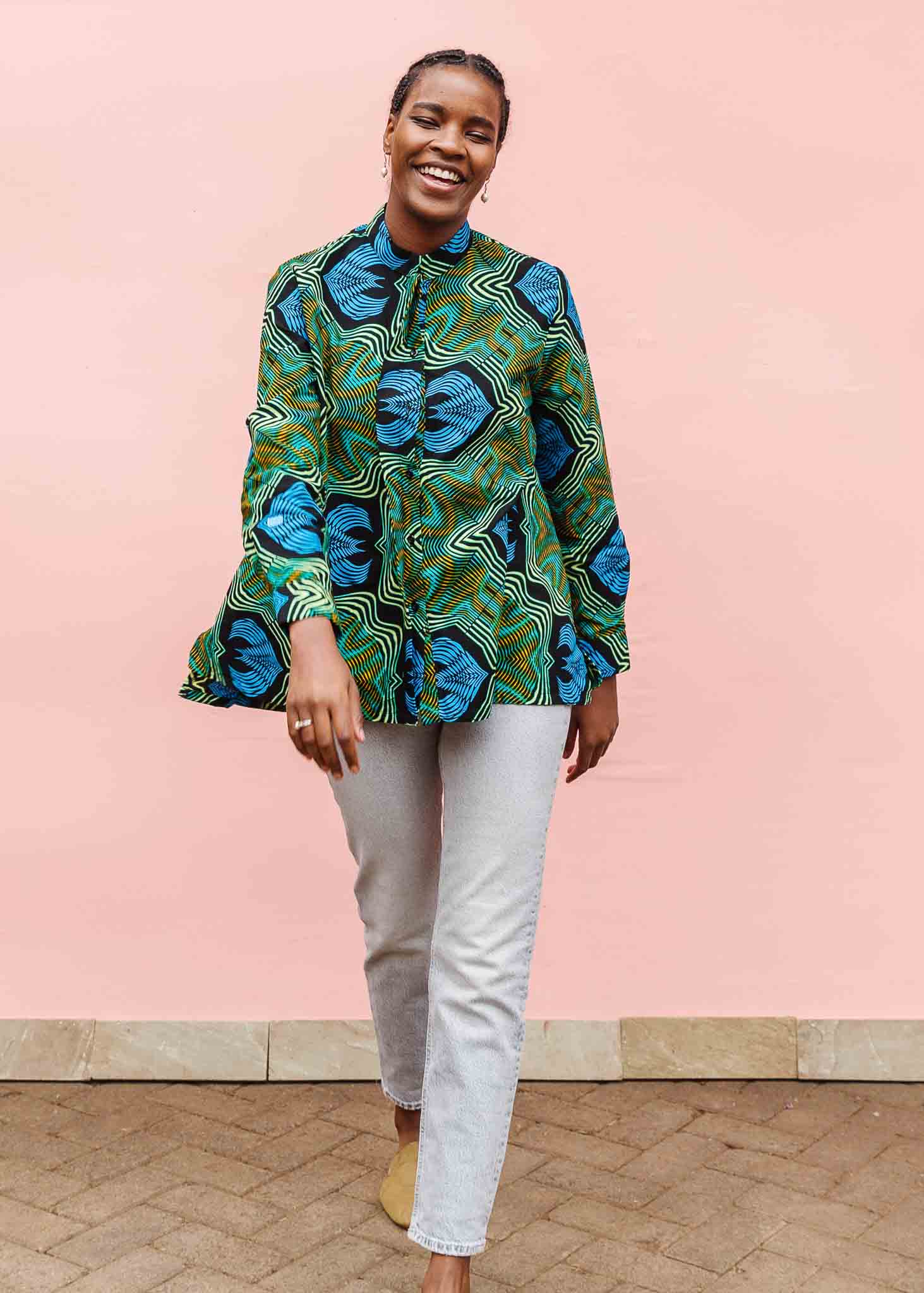 Model wearing long sleeve blouse with blue and green abstract vibration print.