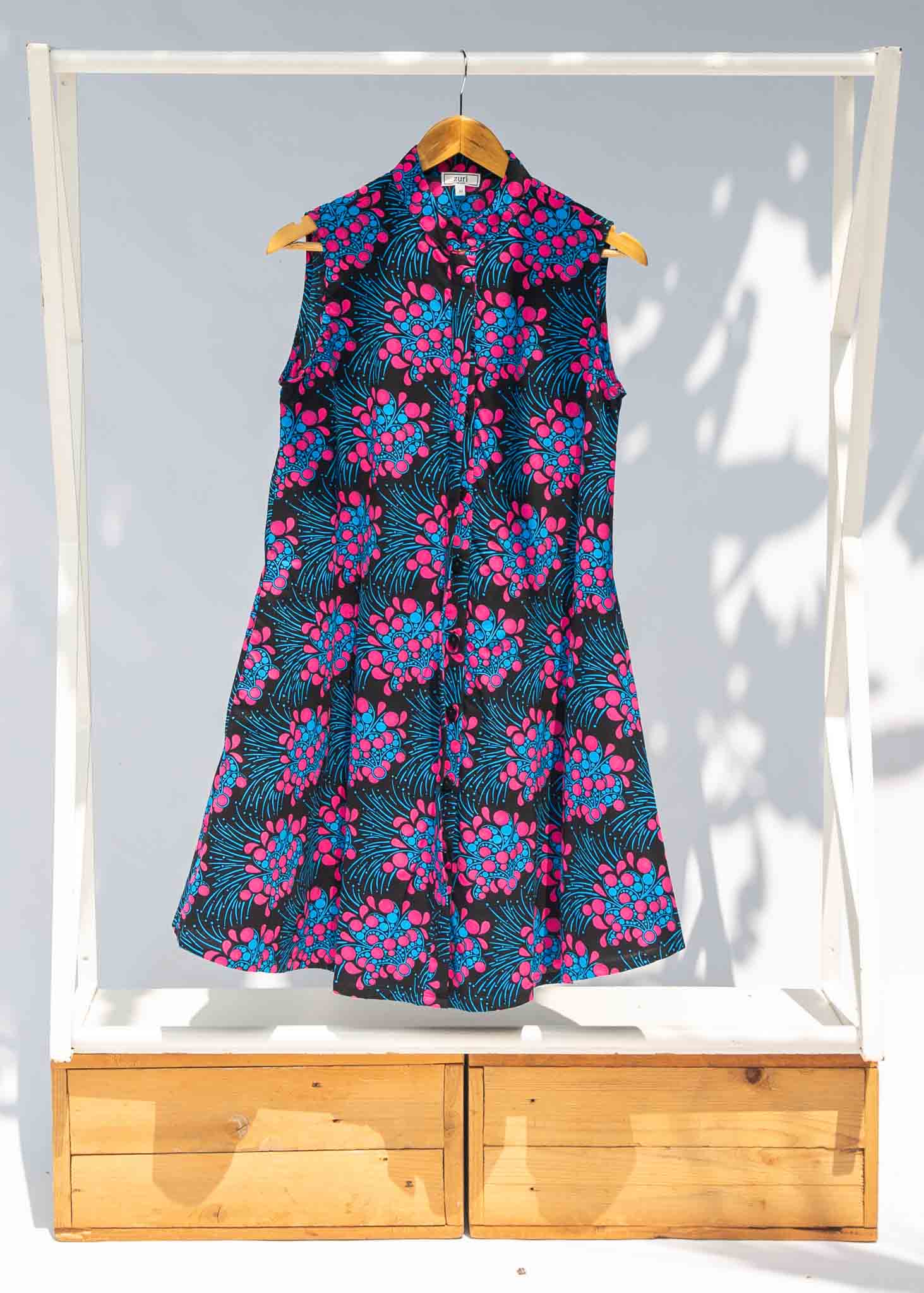 Display of black sleeveless dress with blue and pink poppy print.
