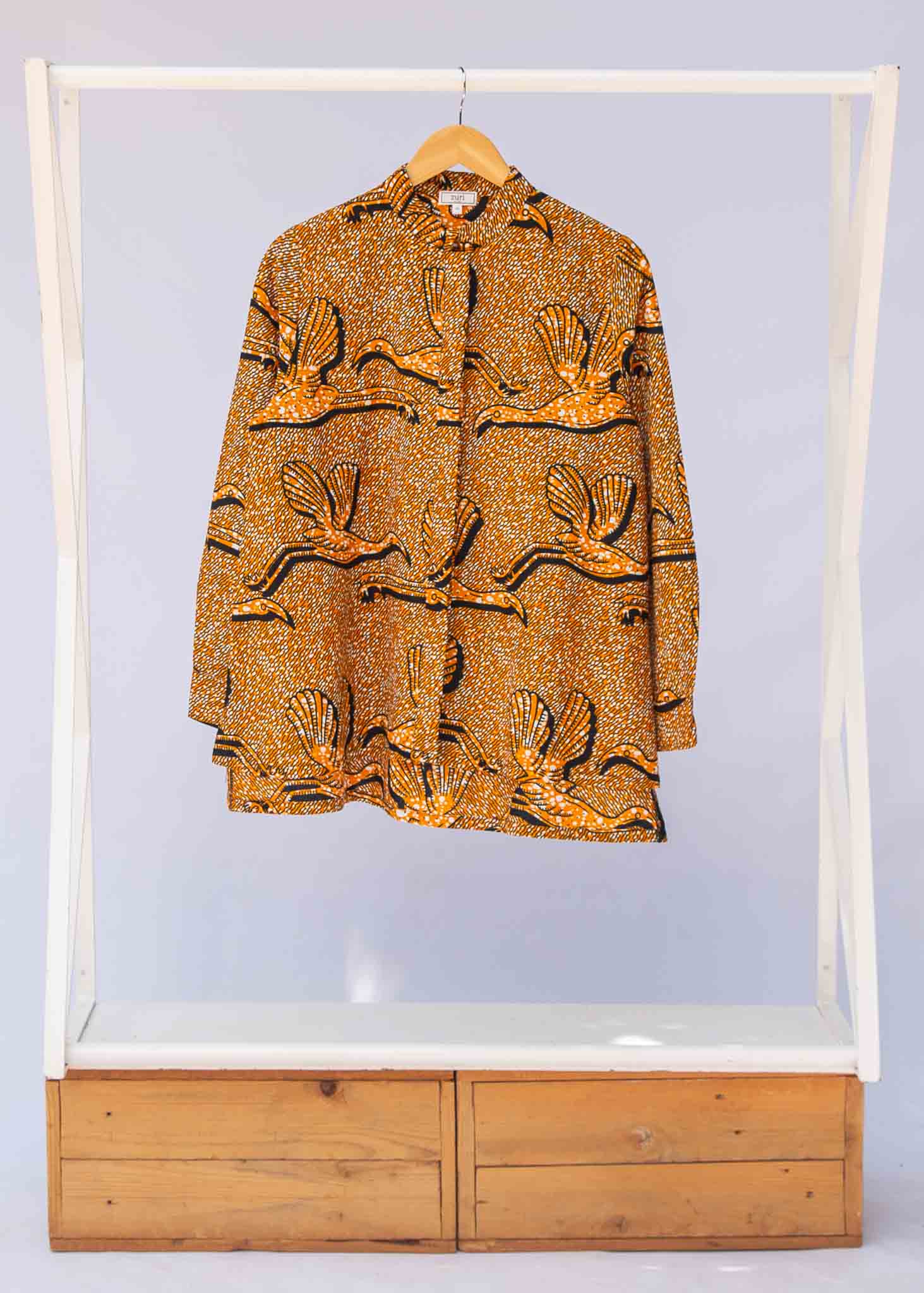 Display of golden yellow shirt with flying bird print.