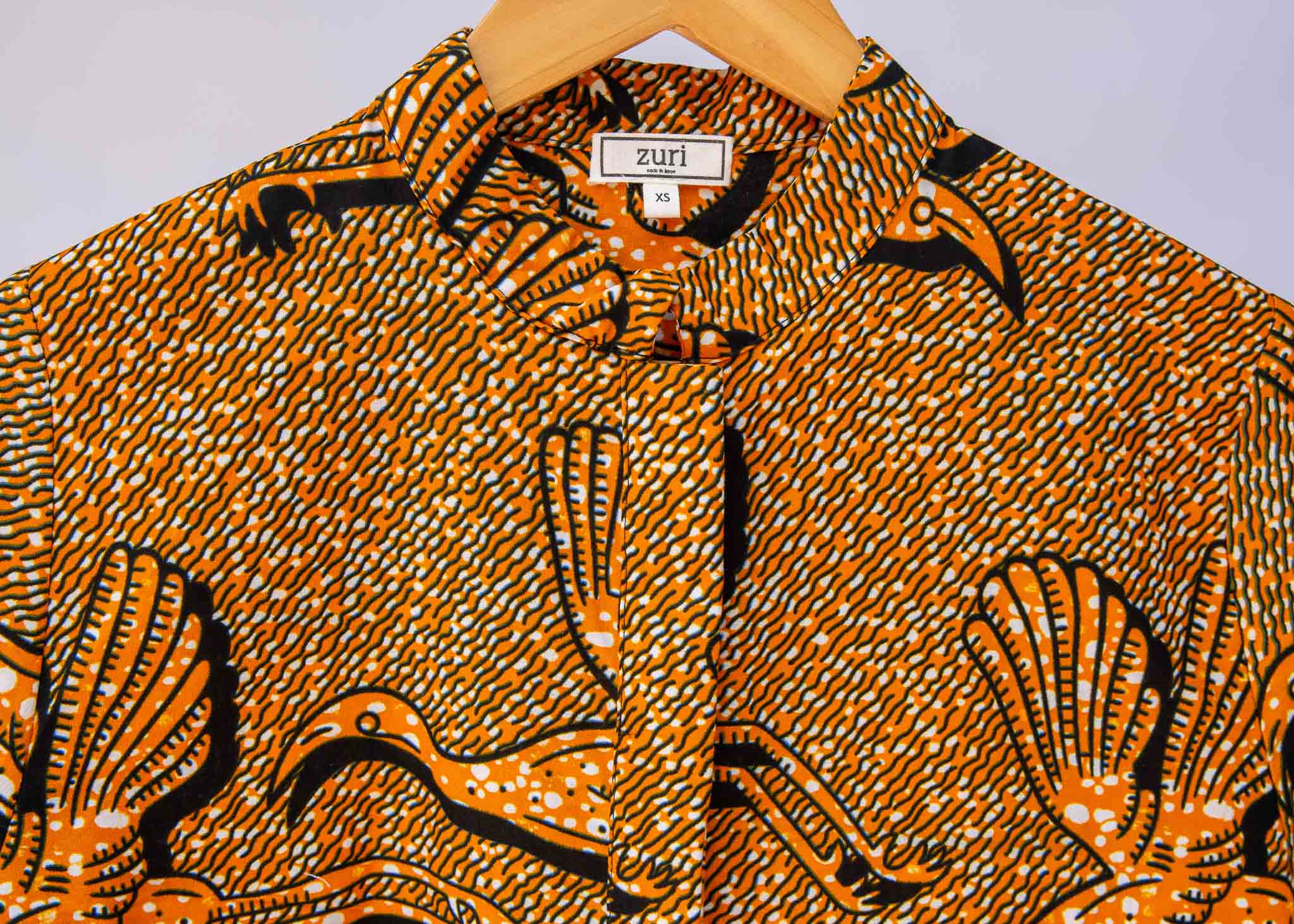 Display of golden yellow shirt with flying bird print.