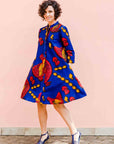 model wearing a rooster and chick design dress in blue, red and orange