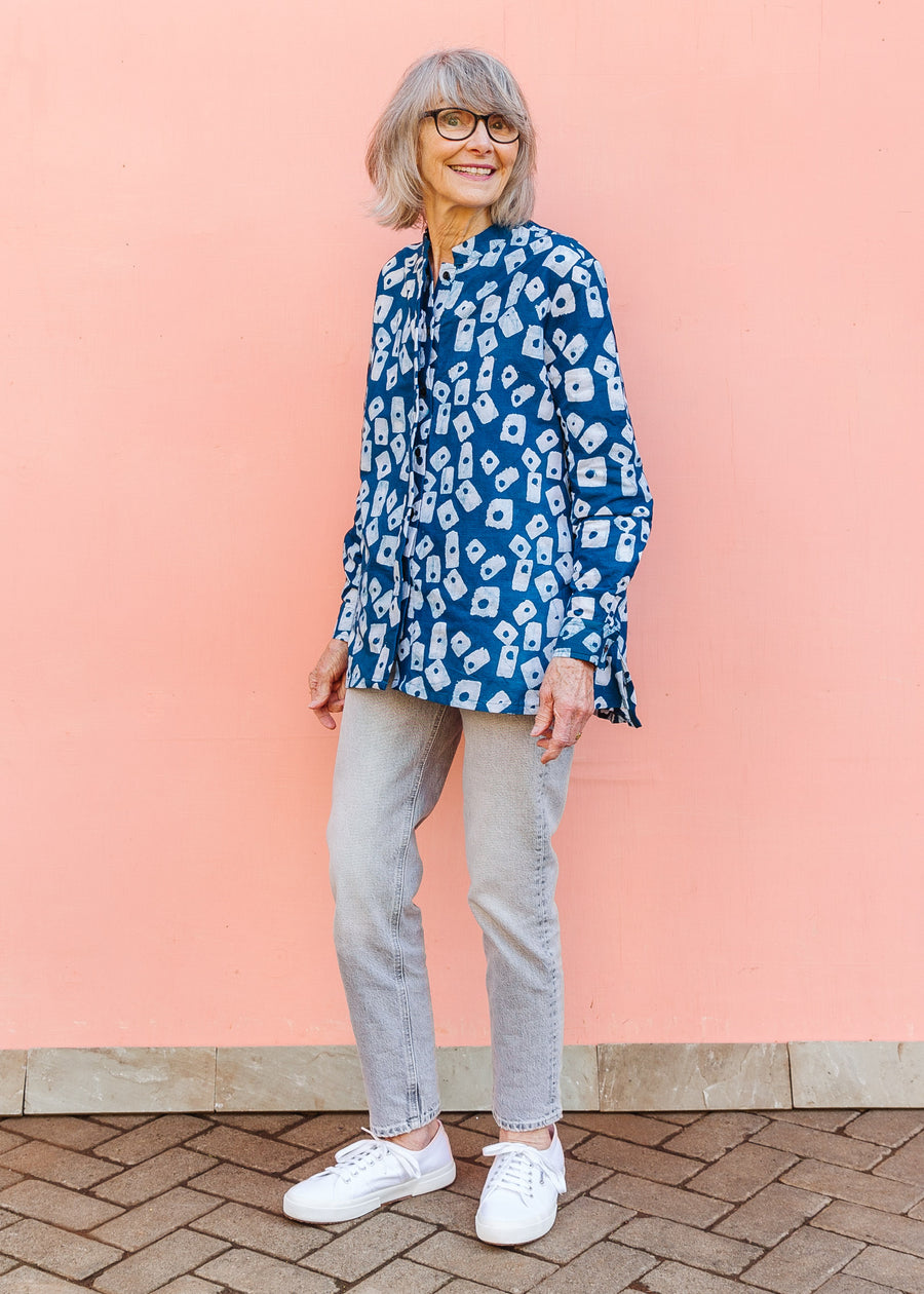 Model wearing blue batik shirt with white domino print, paired with gray jeans and white sneakers.