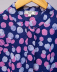 Close up display of purple dress with pink shaded polka dots.