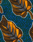 Close up of blue dress with small green swirls and yellow and brown leaves.
