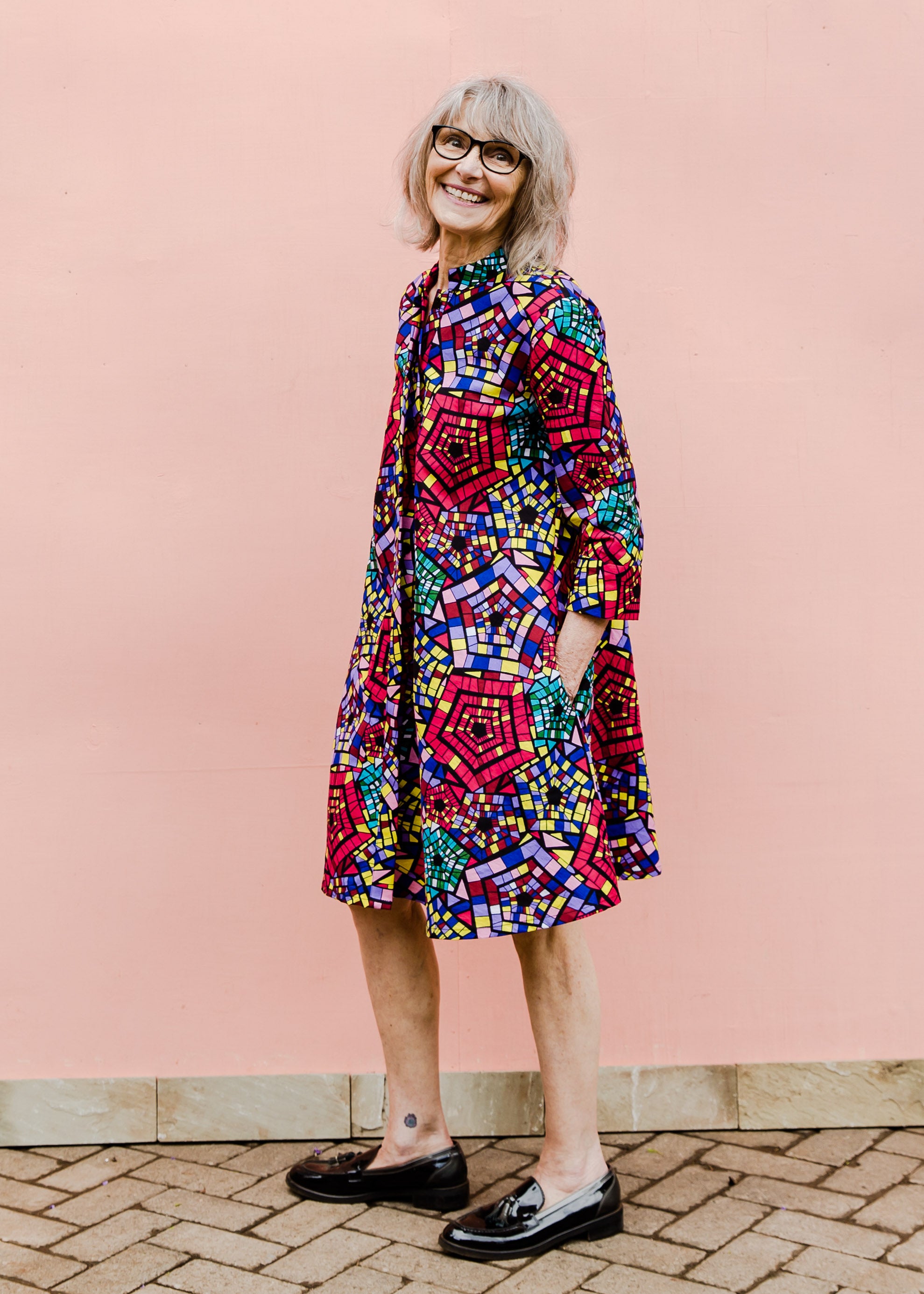 Model wearing rainbow print dress, paired with black loafers.