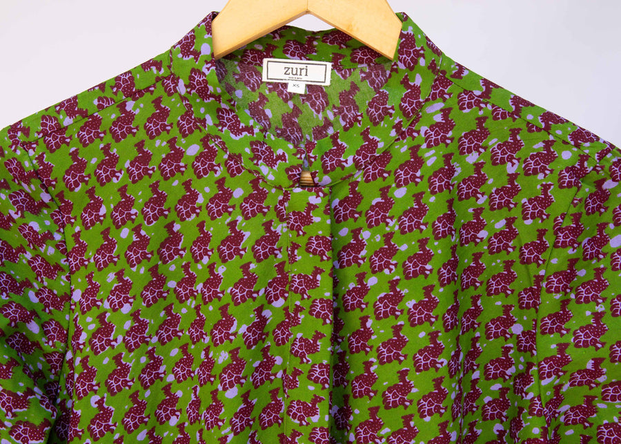 Close up display of green dress with small purple fowl print.