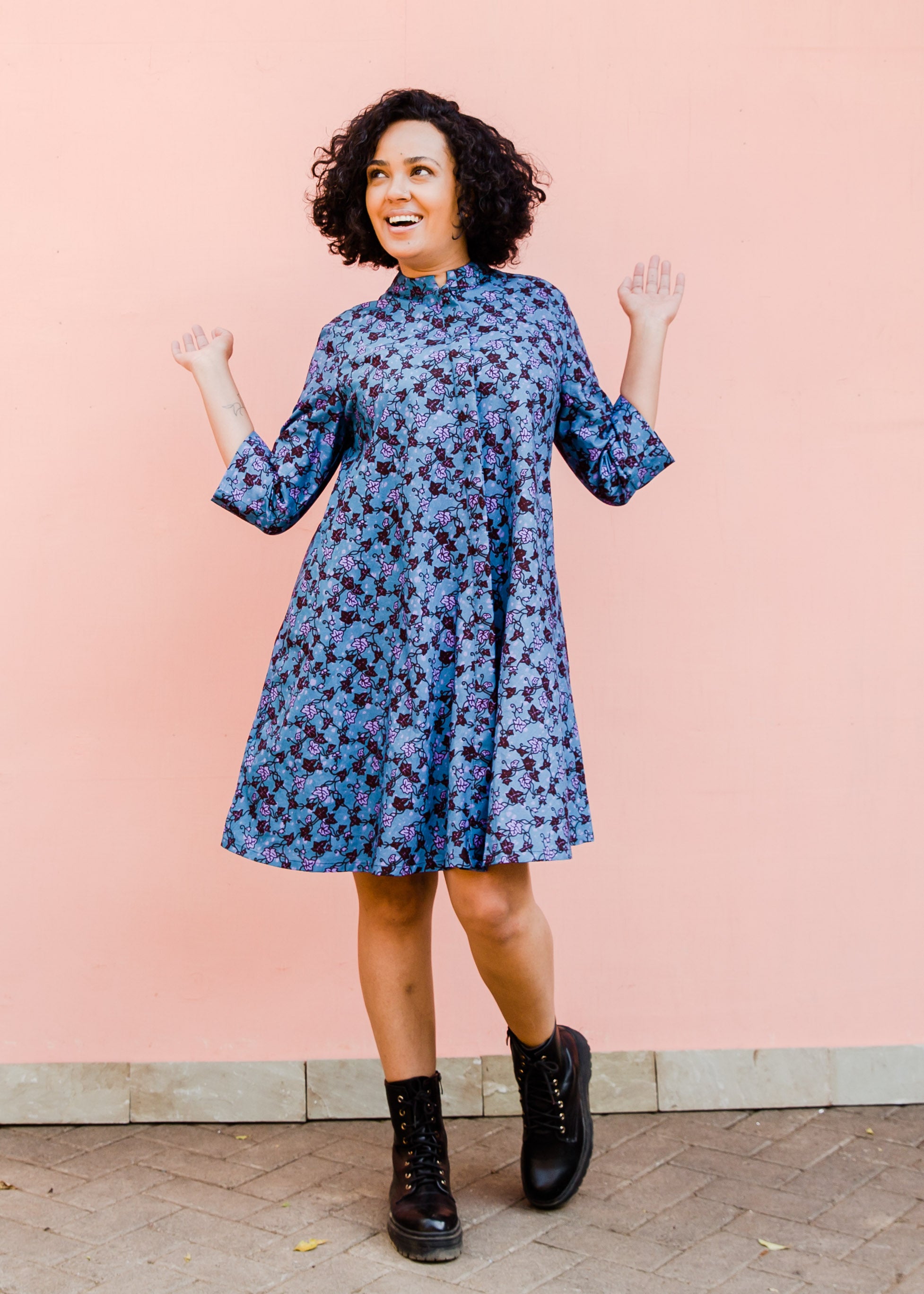Model wearing blue dress with purple flower print, paired with black boots.
